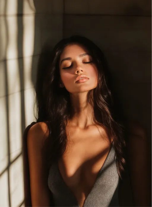 A woman with long dark hair standing in front of a window.